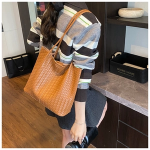 Détail d'un grand sac cabas en cuir tressé marron montrant la texture et la capacité