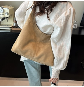 Brown suede hobo tote bag shown on model in a modern minimalist indoor setting