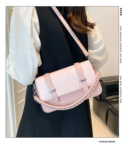 Pink textured crossbody bag shown on model with chic woven handle and metal buckle details