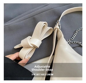Detail of adjustable leather strap with silver chain on beige crossbody bag