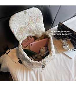 Spacious interior of white quilted backpack with embroidery showing items like a tablet