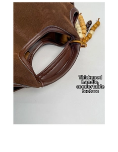 Détail du sac seau en daim avec poignées rondes en cuir et accents de perles en bois