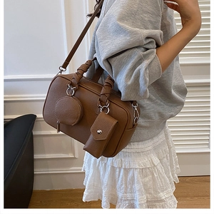 Brown lychee leather Boston bag detail featuring woven handles and mini pouch charms