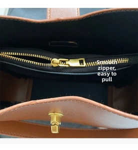Detalle del bolso de cuero marrón con cremallera metálica y compartimento interior