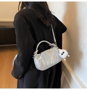 Detail of silver pleated cloud bag with a cute white plush monster charm attachment