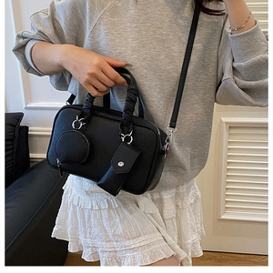 Close-up of black lychee leather Boston bag with detachable round coin purse detail