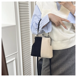 Detail of contrast stitching and vintage metal clasp on a bicolor shell shaped handbag