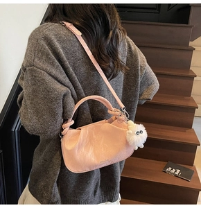 Pink pleated cloud bag with a cute white plush lamb charm on a gray knit outfit