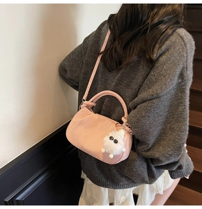Pink pleated bucket bag with monster plush charm and logo detail on white background