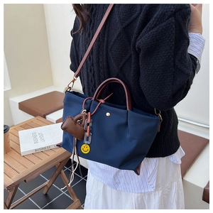 Detailed shot of casual nylon crossbody bag with stylish brown handles and cute charms.
