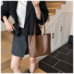 Gros plan sur un sac cabas en cuir tressé marron avec de longues anses et une structure