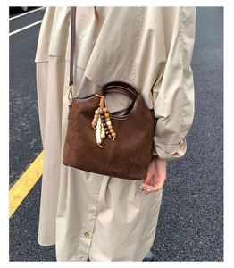 Détail du sac seau en daim marron vintage avec gland perlé ethnique et fine bandoulière
