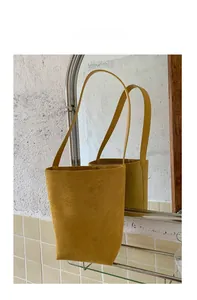 Detailed close-up of mustard yellow suede bucket bag hanging with a mirror reflection