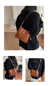 Detail of caramel brown PU leather bucket bag with gold twist lock and strawberry charm