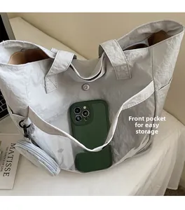 Detail of grey nylon tote bag with transparent front pocket for storage and mini pouch