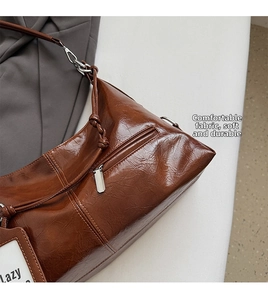 Detail of brown vintage wax leather tote showing wrinkled texture and silver zip pocket
