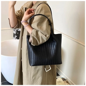 Vue latérale d'un grand sac cabas noir tissé en similicuir porté par un mannequin en studio
