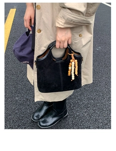Détail du sac cabas en daim noir avec pendentif décoratif en perles de bois en extérieur