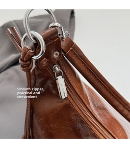 Detail of silver zipper and metal buckle on brown faux leather shoulder bag strap