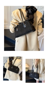 Detail of black suede shoulder bag featuring contrast white stitching and leather handle