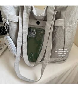 Detail of light grey nylon tote with transparent PVC pocket for phone and accessory pouch