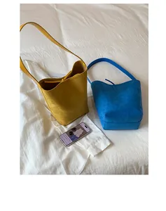 Detail of suede drawstring bucket bags in vibrant yellow and blue with thin leather straps