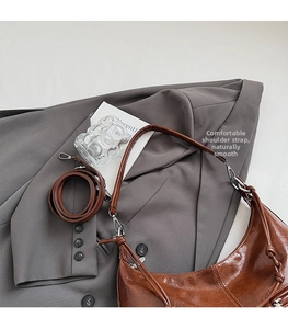 Detail of caramel brown hobo bag with adjustable strap on a gray blazer background
