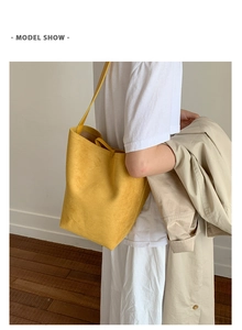Minimalist bright yellow suede bucket bag shown on a model for a casual styling view