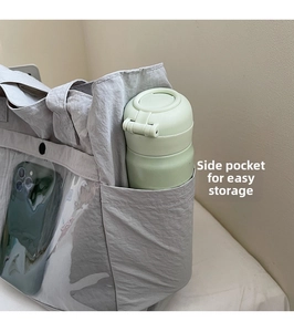Detail of grey canvas tote bag side pocket holding a green thermos and smartphone
