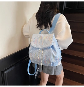 Detail of light blue quilted backpack with colorful wave embroidery and striped drawstring