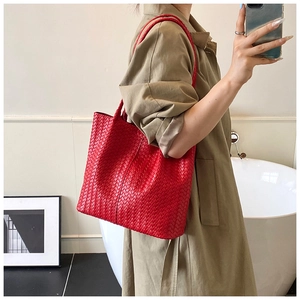 Close-up of red woven leather tote bag with fine texture and slim shoulder straps