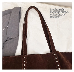 Detailed macro view of deep brown suede tote bag with silver studs and thin straps