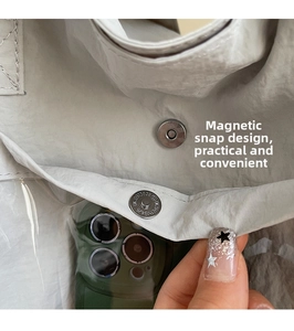 Close-up of canvas tote bag featuring magnetic buckle closure and transparent phone pocket