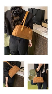 Detail view of a premium brown suede baguette bag with dual zippers and long shoulder straps