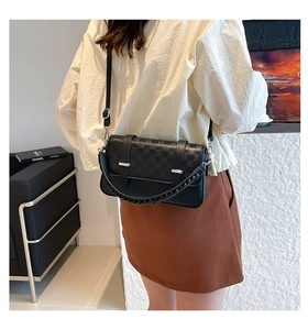 Detail of black leather bag featuring checkered embossing and woven rope handle on model