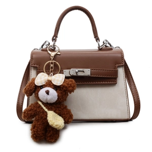 Detailansicht einer braun-beigen Canvas-Handtasche mit Plüschbären-Anhänger.