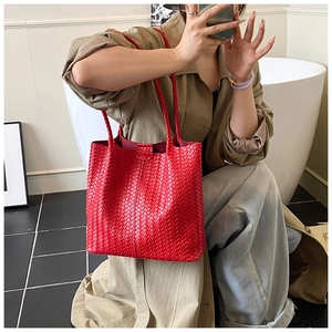 Vue détaillée d'un grand sac cabas rouge tressé porté par un mannequin en extérieur