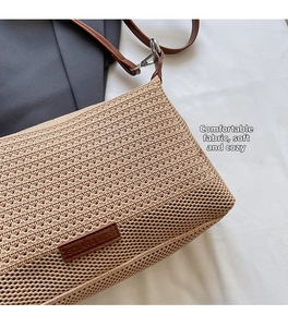 Dettaglio della borsa a spalla in paglia intrecciata con patch logo in pelle e metallo