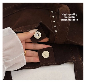 Detail of magnetic snap closure and silver rivets on dark brown suede tote bag