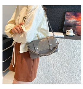 Detail of grey crossbody bag featuring checkered embossing and woven leather handle