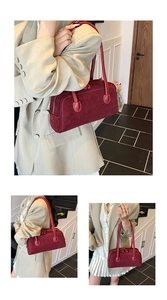 Macro detail of wine red suede handbag showing white contrast stitching and dual handles