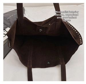 Spacious interior of dark brown suede tote bag with rivet trim and magnetic closure