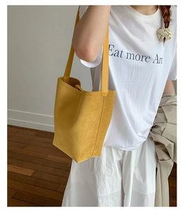 Bright yellow suede tote bag with slim shoulder straps worn by model for daily outfit