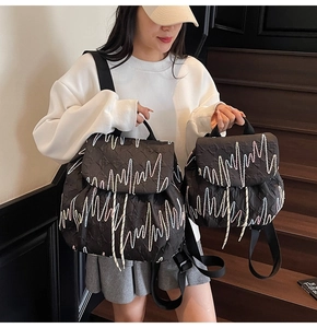 Comparison of large and small black quilted backpacks with colorful zigzag embroidery