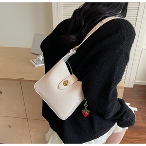 Detalle de bolso cubo de cuero sintético blanco crema con cierre dorado y fresa