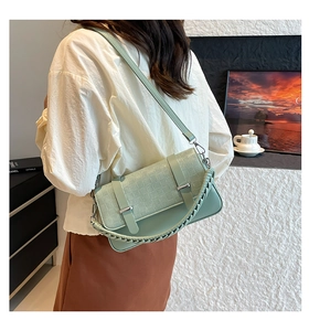 Detail showing light green textured faux leather surface and woven handle on the bag