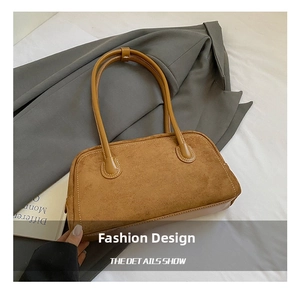 Detail of brown suede baguette bag with cylindrical handles on grey blazer