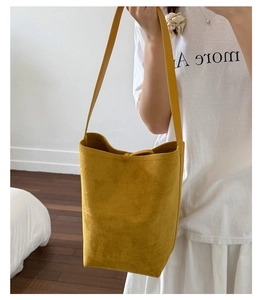 Ginger yellow matte suede bucket bag shown worn on shoulder for style and size scale