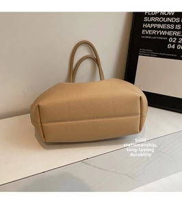 Detail of beige lychee grain leather tote bag showing sturdy texture and double handles