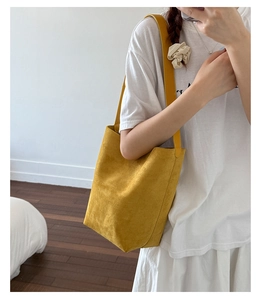 Detail of yellow suede bucket bag featuring minimalist design and soft tote texture